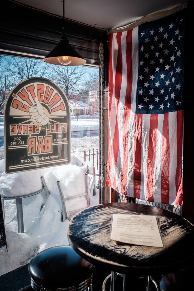 A table inside Trusty's, next to the window, with the American flag hanging from the wall.