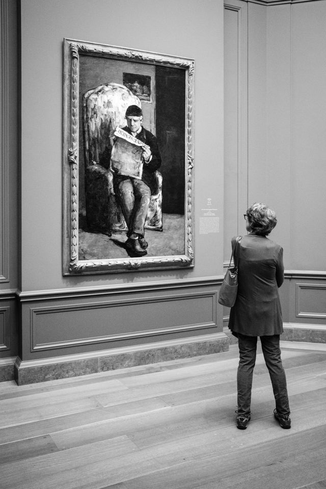 A person examining Cézanne's "The Artist's Father", at the National Gallery of Art.