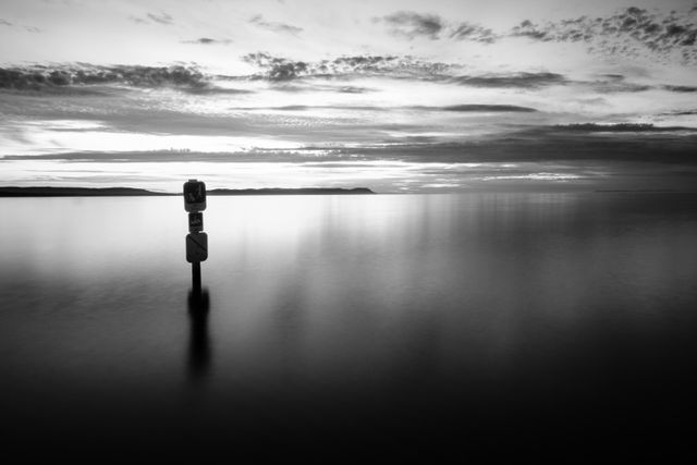 Long exposure of a park sign partially submerged in the surf of Good Harbor Bay Beach after sunset.