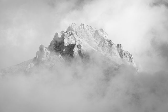 The summit of Teewinot Mountain seen among clouds.