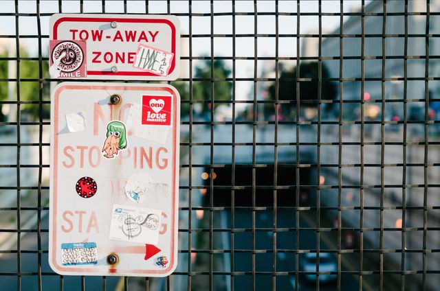 A faded traffic sign covered in stickers on an overpass near the National Mall in Washington, DC.