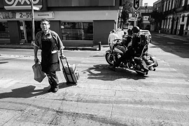 A man crossing the street while a motorcycle drives by, at Calle de Balderas in Mexico City.