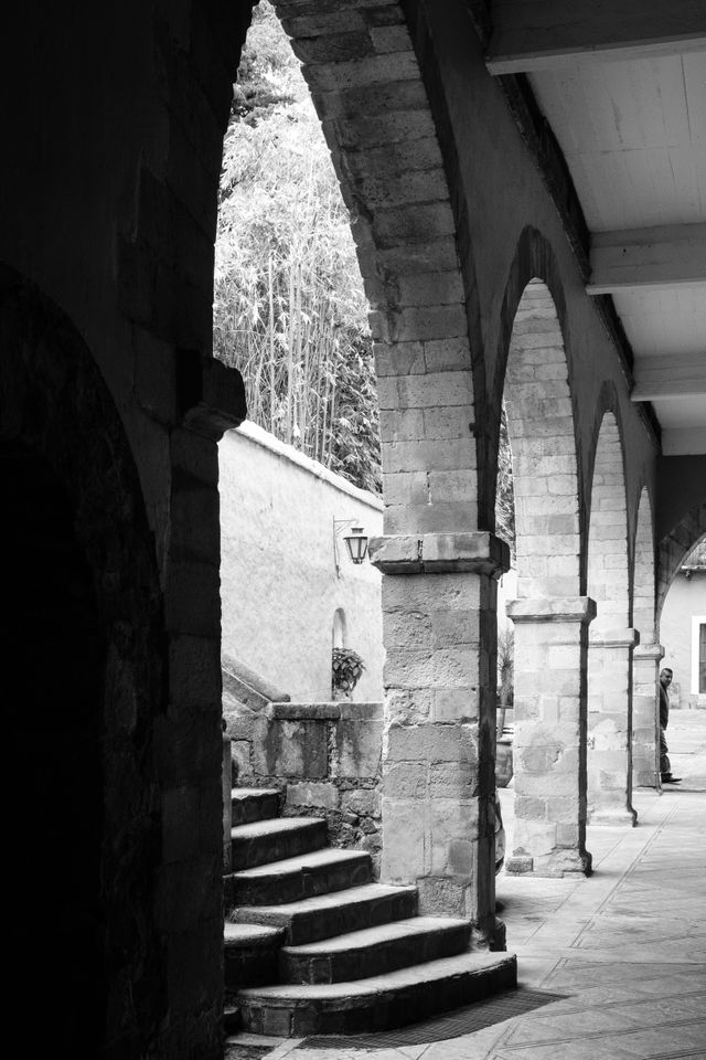 A man peeking from behind a series of columns at San Ángel, Mexico City.