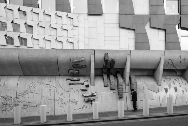 A pedestrian walking in front of the Scottish Parliament Building.