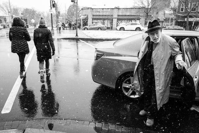 A man exiting a taxi near Eastern Market on a snowy day.