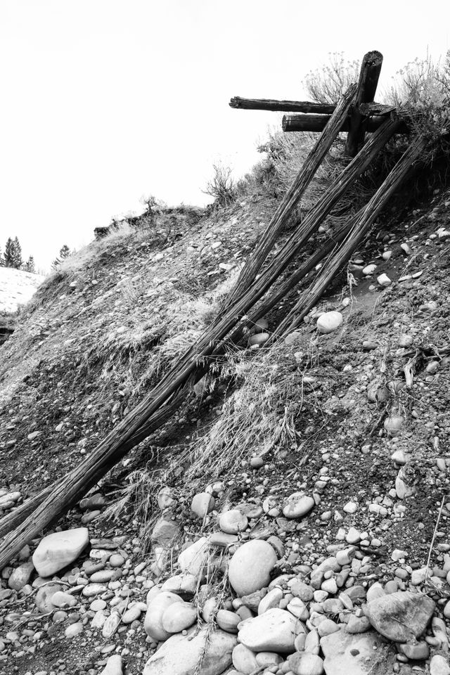 A fallen wooden fence in a small hill with some rocks.