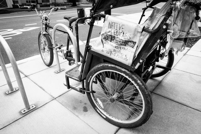 Close-up of an empty pedicab parked on the curb.