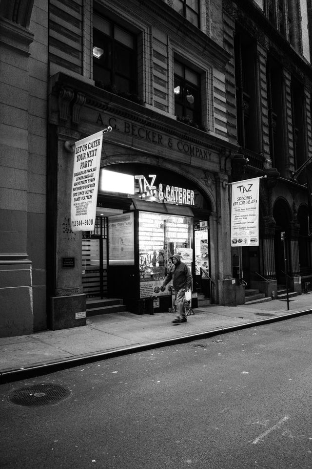 A man walking in front of Taz Cafe & Caterer in the Financial District in New York City.